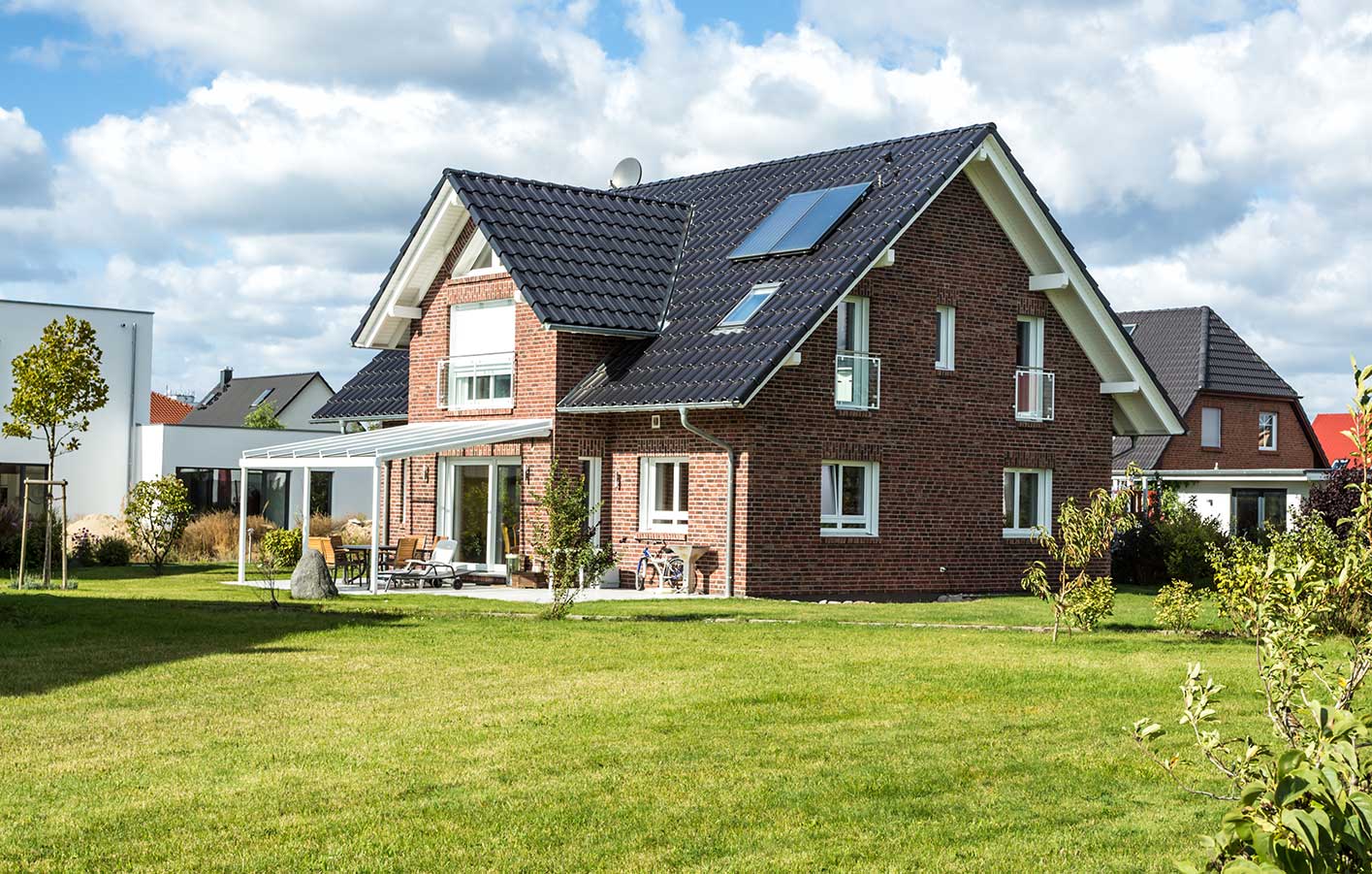 Blick auf rotes Backstein Einfamilienhaus mit Terrassenüberdachung